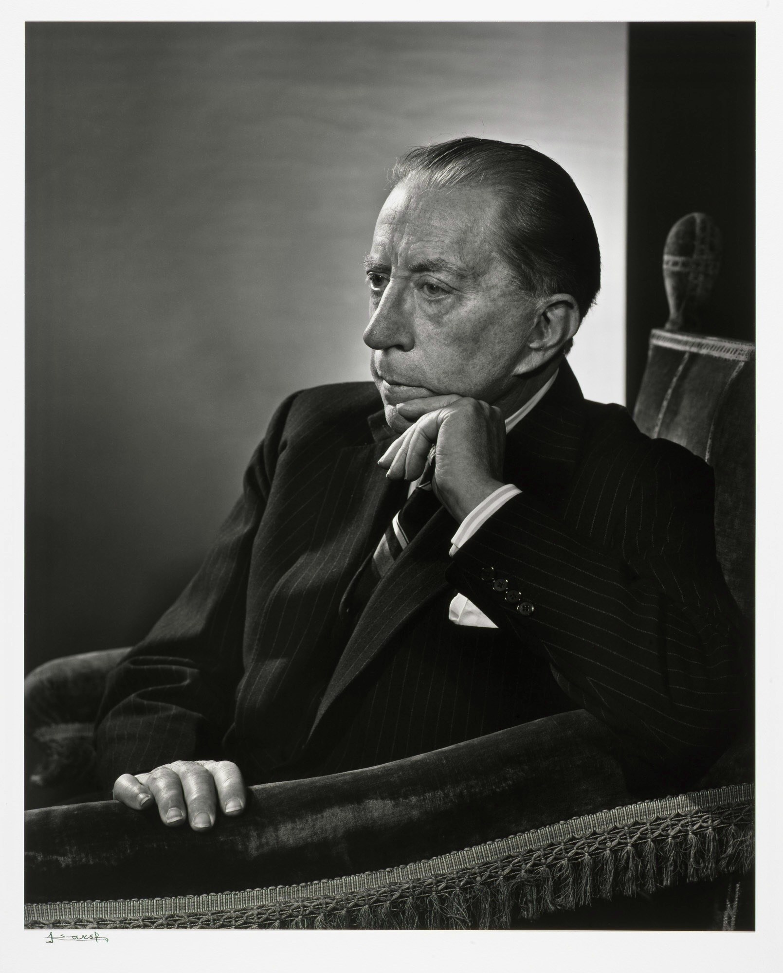 A person in a suit sitting in a chair Description automatically generated with medium confidence