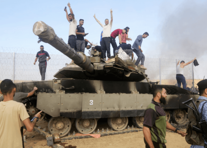 Palestinians take control of an Israeli tank after crossing the boundary fence with Israel from the southern Khan Younis area of the Gaza Strip on 7 October.