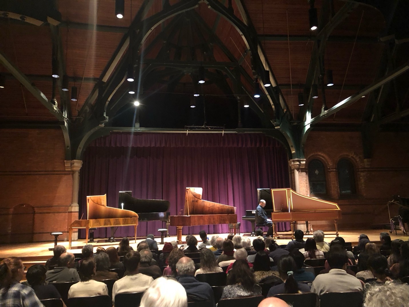 A group of people sitting in a room with a piano Description automatically generated