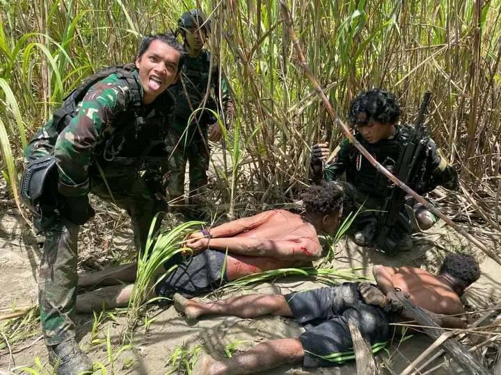 Photo of men lying on the ground with Indonesian soldiers around them