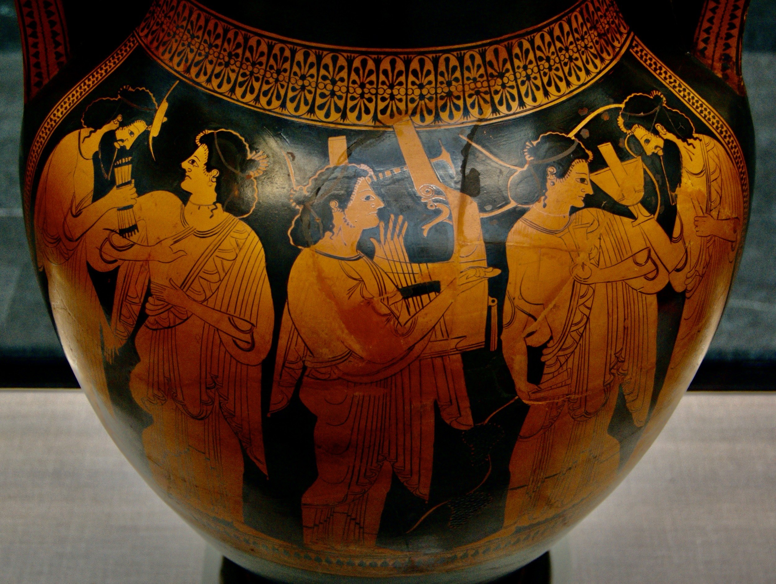 A black and orange vase with people on it Description automatically generated