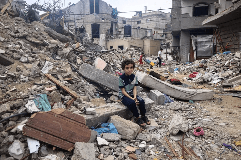 A child sitting on a pile of rubble Description automatically generated