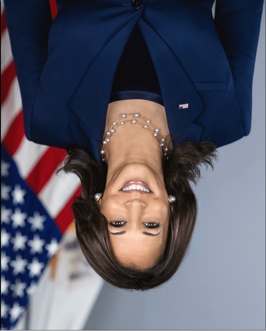 A person smiling with a flag behind her Description automatically generated